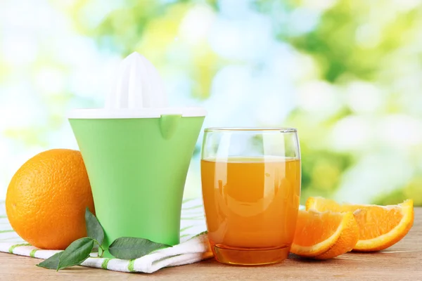 Citruspress, glas juice och mogna apelsiner på brun träbord — Stockfoto