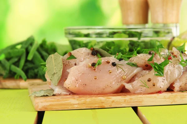Mięso z kurczaka w szklanej płytce, zioła i przyprawy na stole na tle przyrody — Zdjęcie stockowe