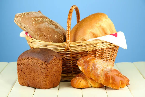 Composizione con pane e panini, in cesto di vimini su tavolo di legno, su sfondo a colori — Foto Stock