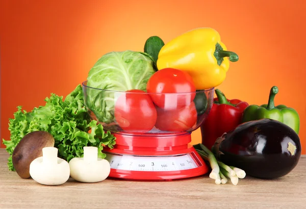 Fresh vegetables in scales on table on orange background — Stock Photo, Image