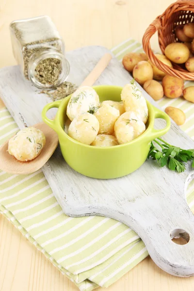 Inschrijving van jonge aardappelen met zure room en kruiden in pan op een houten bord op tabel close-up — Stockfoto