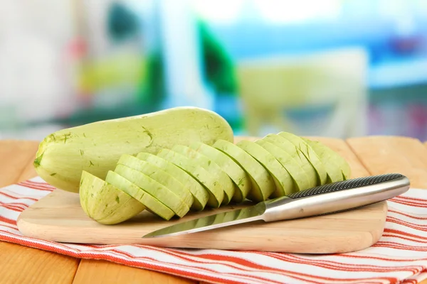 Verse courgettes op snijplank, op houten tafel, op lichte achtergrond — Stockfoto