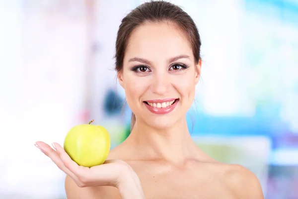 Mulher sorridente com maçã no fundo brilhante — Fotografia de Stock
