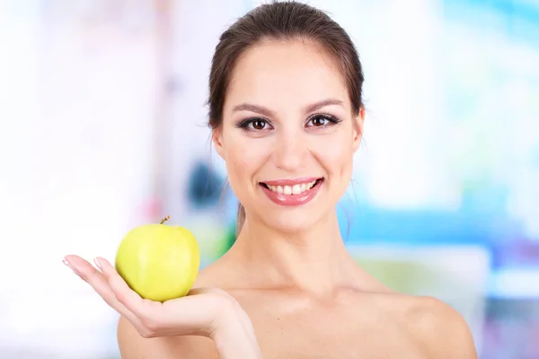 Smiling woman with apple on bright background — Stock Photo, Image