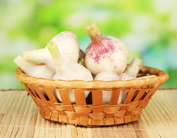 Fresh garlic in wicker basket, on bright background — Stock Photo, Image