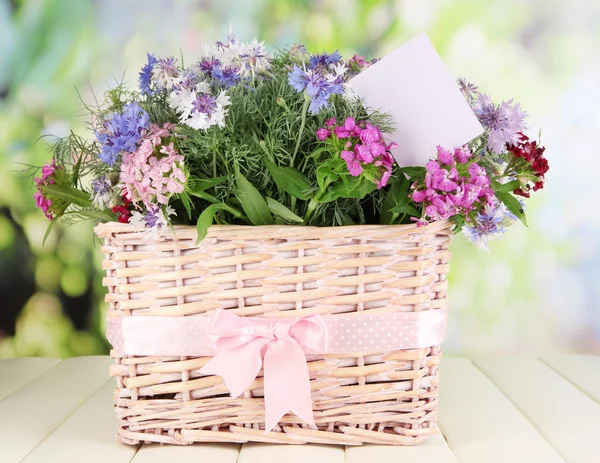 Beautiful bouquet in basket on wooden table on natural background — Stock Photo, Image