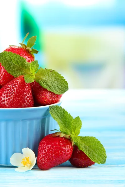 Ripe sweet strawberries in bowl on blue wooden table — Stock Photo, Image