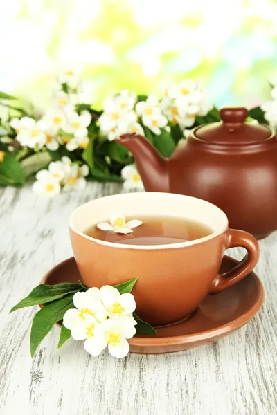 Xícara de chá com jasmim, na mesa de madeira, no fundo brilhante — Fotografia de Stock