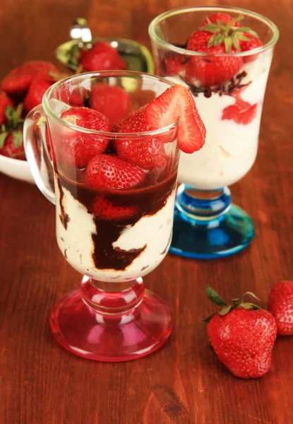 Deliziosi dessert alla fragola in vaso di vetro su tavolo di legno primo piano — Foto Stock