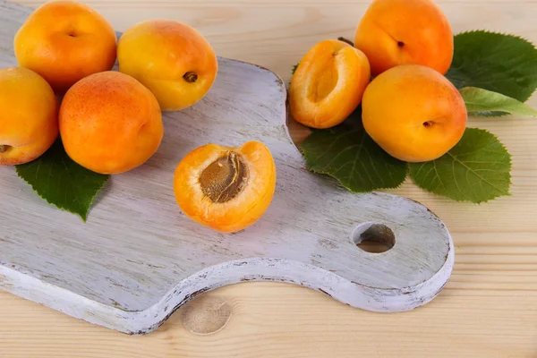 Apricots on board on wooden table — Stock Photo, Image