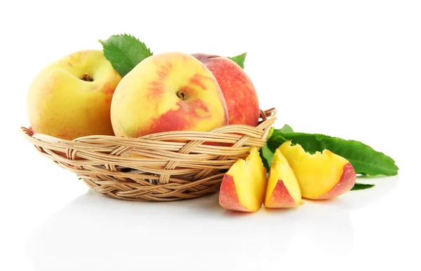 Rijpe zoete perziken met bladeren in de mand, geïsoleerd op wit — Stockfoto