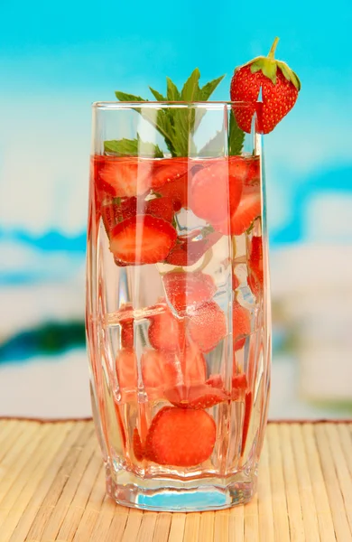 Vaso de bebida de frutas con cubitos de hielo sobre fondo azul — Foto de Stock