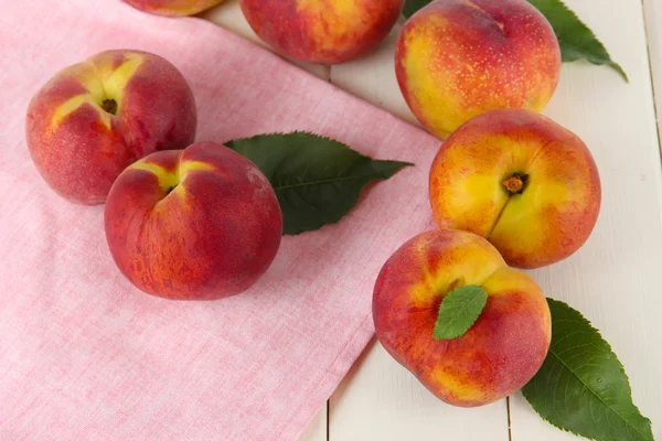 Peaches on napkin on wooden table — Stock Photo, Image