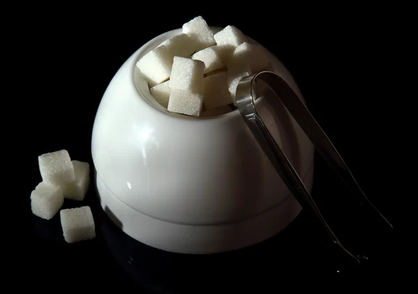 Refined sugar in white sugar bowl on black background — Stock Photo, Image