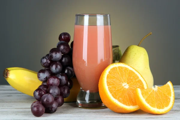 Glass of fresh juice on table on gray background — Stock Photo, Image