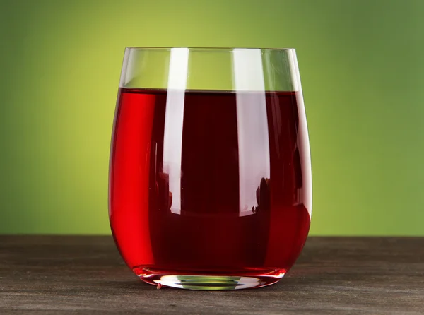 Glass of fresh garnet juice on table on green background — Stock Photo, Image