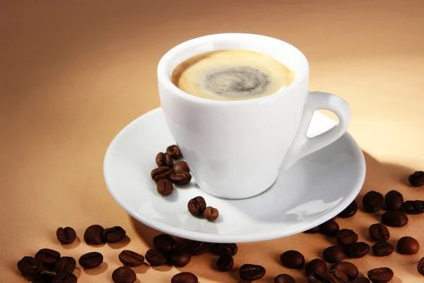 Cup of coffee with coffee beans on beige background — Stockfoto