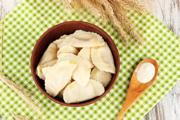 Tasty dumplings with fried onion on brown plate, on wooden background — Stock Photo, Image