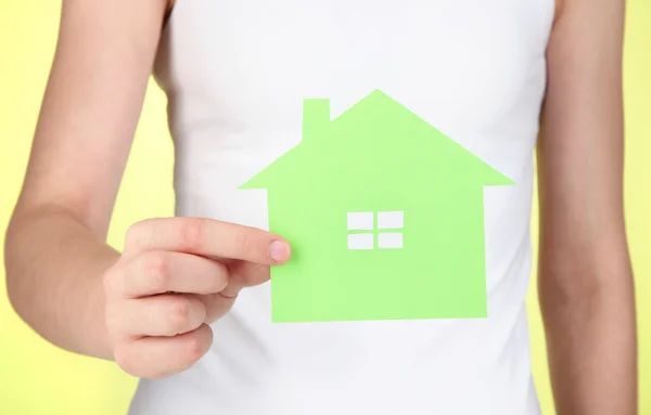 Paper house in hand on green background — Stok fotoğraf