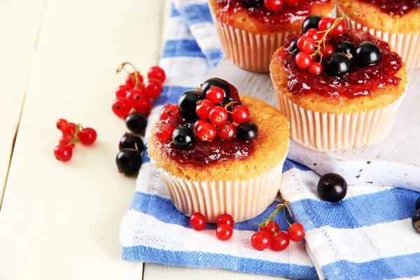 Smakelijke muffins met bessen op witte houten tafel — Stockfoto