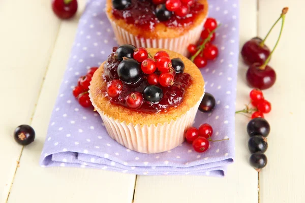 Smakelijke muffins met bessen op witte houten tafel — Stockfoto