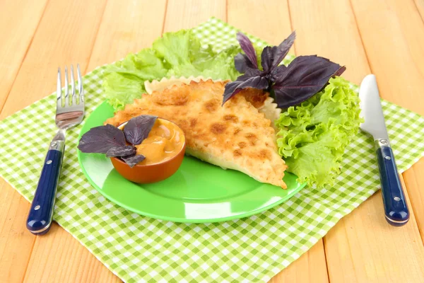 Sabrosos chebureks con hierbas frescas en el plato, sobre fondo de madera — Foto de Stock