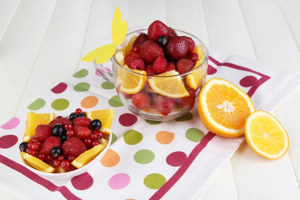 Ensalada de frutas útil en taza de vidrio y tazón en mesa de madera de primer plano —  Fotos de Stock