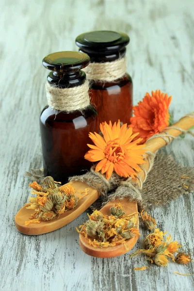 Medicine bottles and calendula flowers on wooden background — Stock Photo, Image