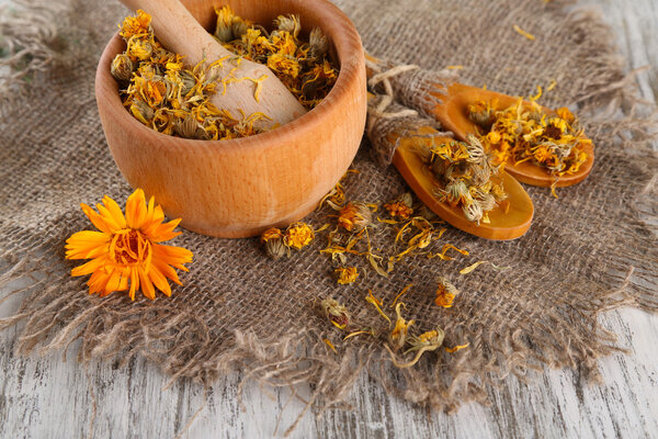 Свежие и сушеные цветы календулы в растворе на деревянном фоне
