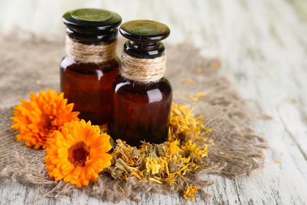 Medizinflaschen und Ringelblumen auf Holzgrund — Stockfoto