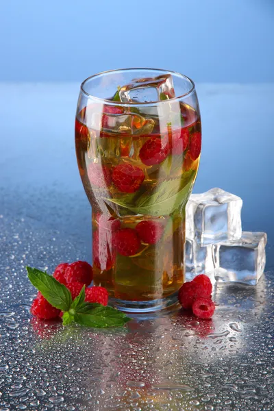 Iced tea with raspberries and mint on blue background — Stock Photo, Image
