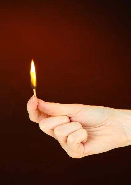 Burning match in female hand, on dark brown background — Stock Photo, Image
