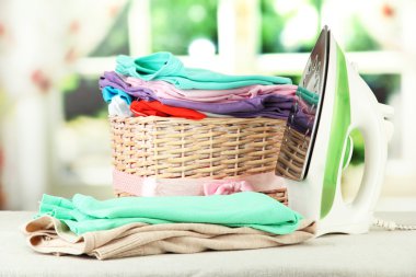 Buharlı Ütü ve parlak arka plan üzerinde elbise ile hasır sepet