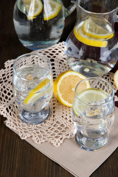 Glas kannor vatten och glasögon på träbord närbild — Stockfoto