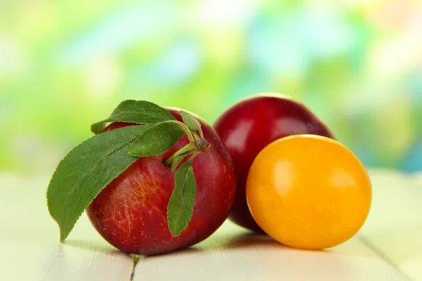 Ripe plums on wooden table on natural background — Stock Photo, Image