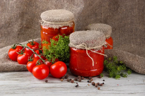 Sabrosos tomates enlatados y frescos sobre mesa de madera — Foto de Stock