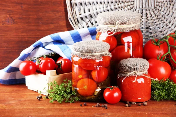 Sabrosos tomates enlatados y frescos sobre mesa de madera — Foto de Stock