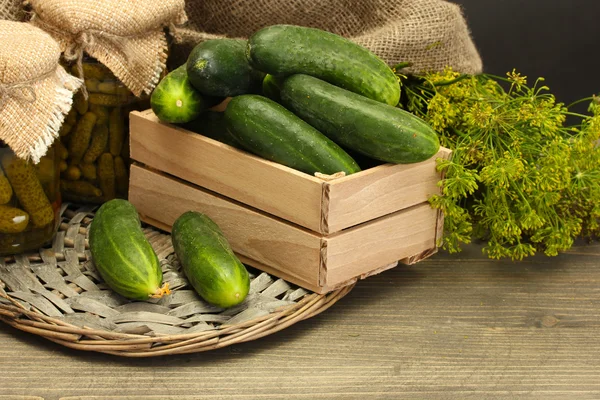 Färska gurkor i trälåda, pickles och dill, på grå trä bakgrund — Stockfoto