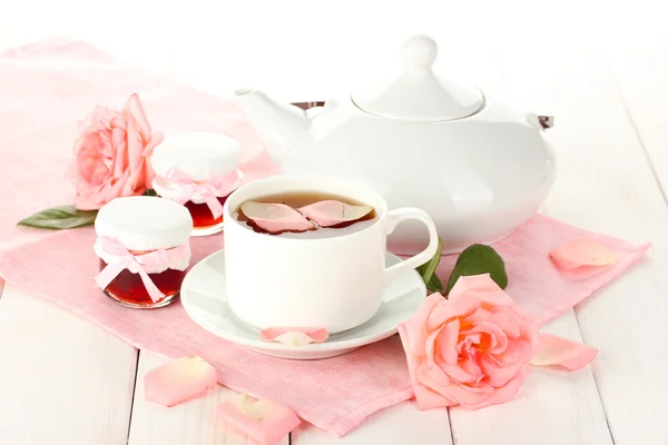 Tetera y taza de té con rosas y mermelada sobre mesa de madera blanca —  Fotos de Stock