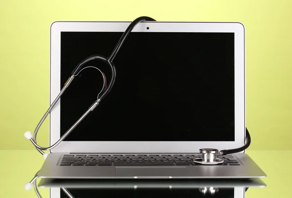 Silver notebook with a stethoscope on yellow background with reflection close-up — Stock Photo, Image