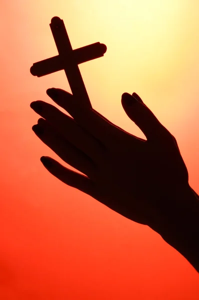 Female hands with crucifix, on red background — Zdjęcie stockowe