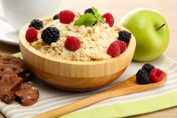 Tasty oatmeal with berriesand cup of tea, on wooden table — Stock Photo, Image