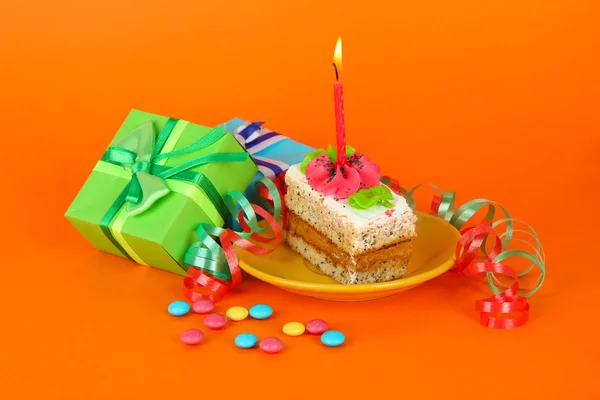 Bolo de aniversário colorido com vela e presentes no fundo laranja — Fotografia de Stock