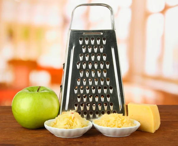 Metal grater and cheese, apple on bright background — Stock Photo, Image