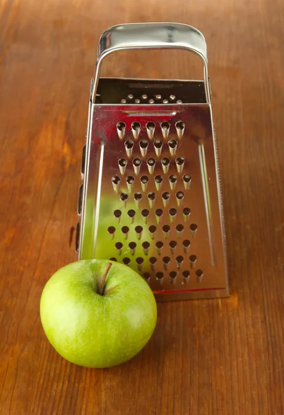 Rallador de metal y manzana, sobre fondo de madera — Foto de Stock
