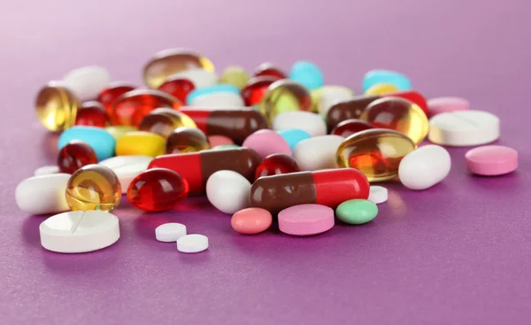 Assortment of pills, tablets and capsules on purple background — Stock Photo, Image