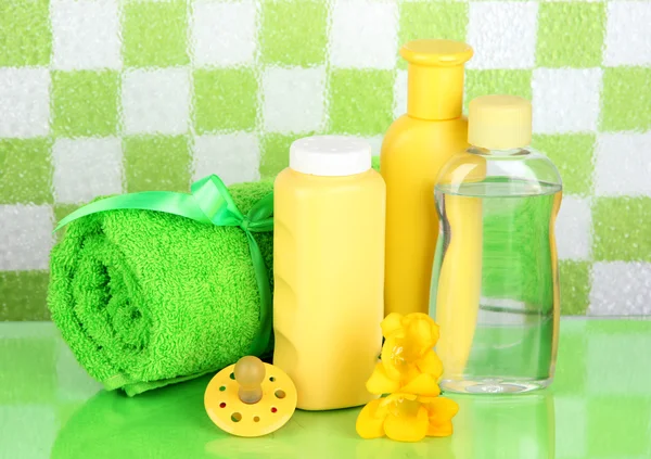 Cosméticos para bebés y toalla en el baño sobre fondo de pared de azulejos verdes —  Fotos de Stock