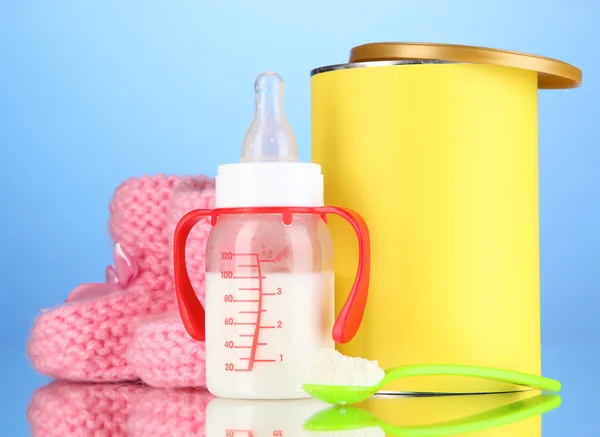 Biberón con leche y comida para bebés sobre fondo azul —  Fotos de Stock