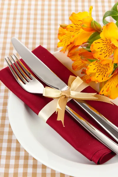 Накрытие праздничного обеденного стола с цветами на клетчатом фоне — стоковое фото