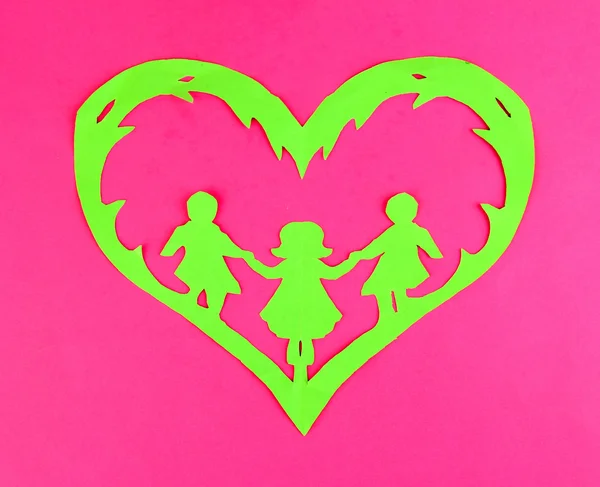 Green cut out paper heart with people inside, on color background — Stock Photo, Image